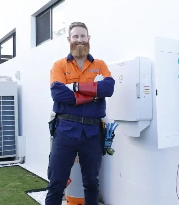 Evolved Solar Owner, Steven Hord, standing with arms crossed, smiling in front of an electrical panel at an indoor industrial or utility setting.